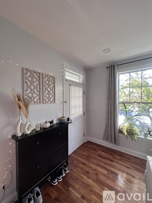 A room with a black dresser and wooden floors.