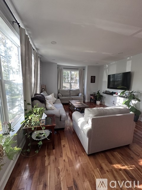 A living room with a white couch and wooden floors.