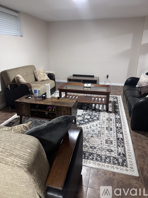 A living room with a rug, a couch, a chair, and a coffee table.