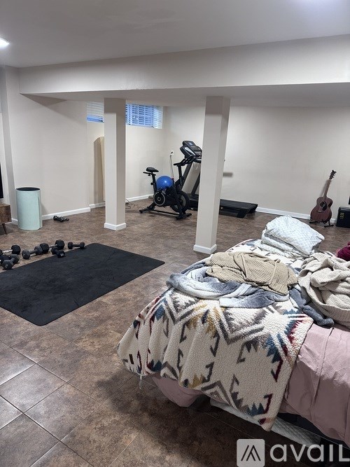 A room with a bed, a gym setup, and a guitar.