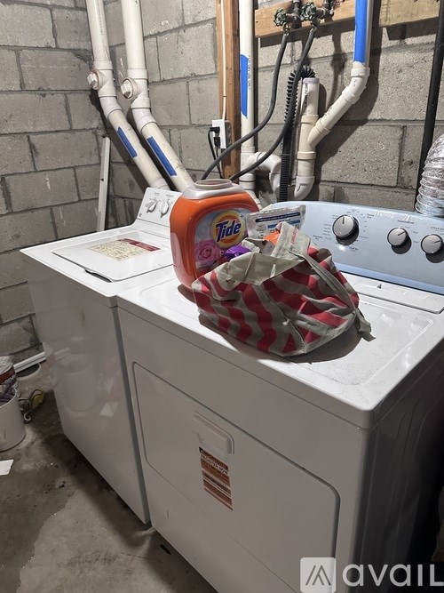 A white washing machine with a red and white bag on top of it.