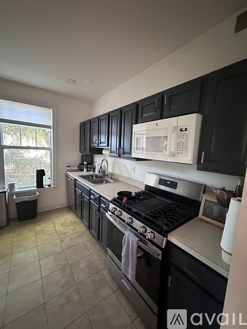 A kitchen with black cabinets and a white microwave.