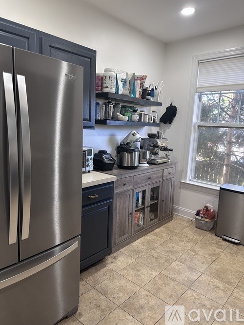 A kitchen with a stainless steel refrigerator and a window.