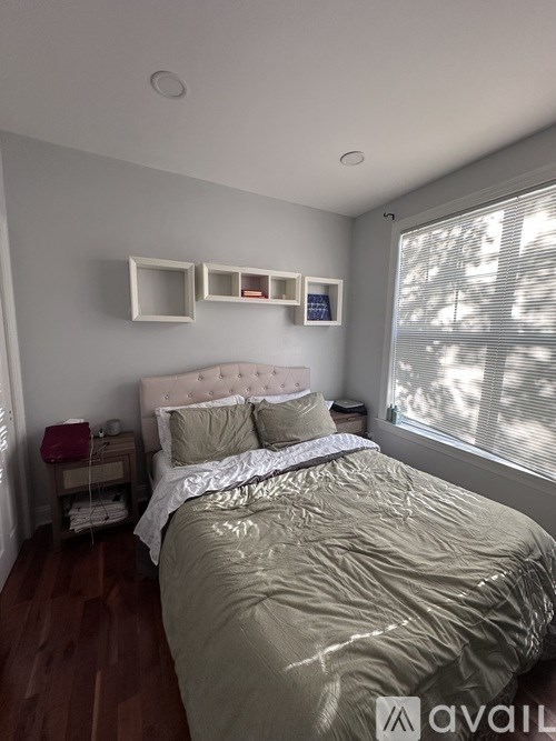 A bedroom with a bed, nightstand, and a window with blinds.