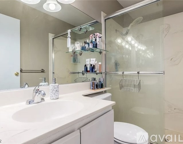 A bathroom with a white sink and a glass shower door.