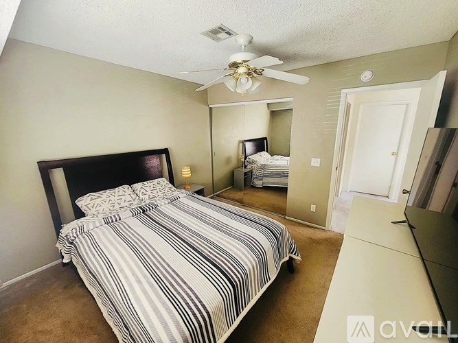 A bedroom with a large bed and a ceiling fan.