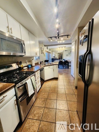 A kitchen with white cabinets and a black fridge.