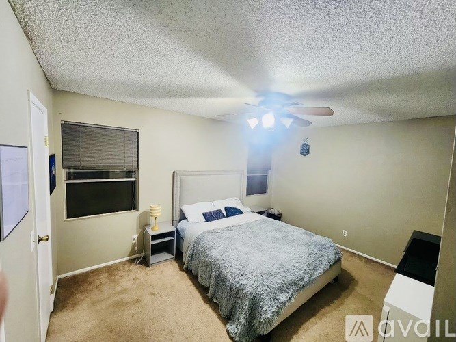 A bedroom with a bed, nightstand, and window.