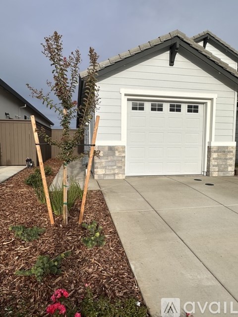 A small house with a white garage door and a brown roof.