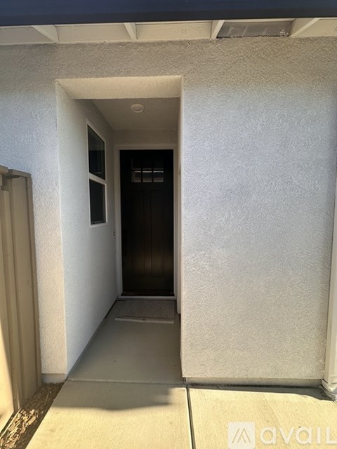 A hallway with a door on the left and a wall on the right.