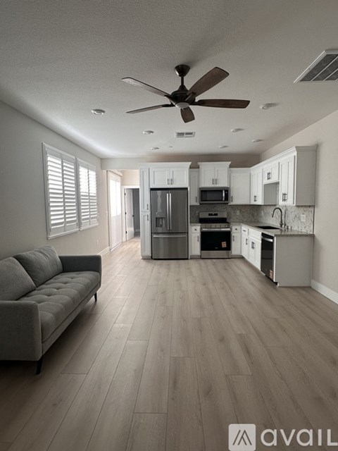 A spacious kitchen and living room with a grey sofa and wooden flooring.