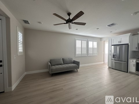 A spacious kitchen and living room with a grey sofa and wooden floors.