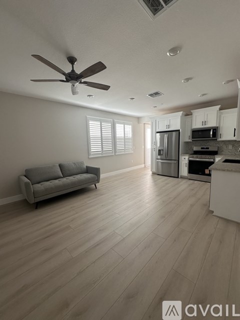 A spacious kitchen and living room with a grey sofa and wooden flooring.