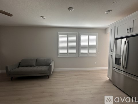 A kitchen with a refrigerator and a couch with a window.