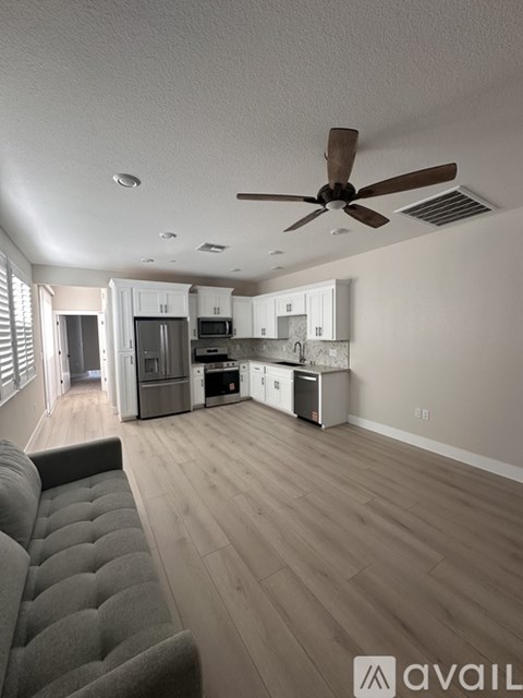 A living room with a grey couch and a kitchen in the background.