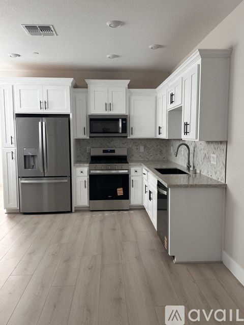 A kitchen with white cabinets and a stainless steel refrigerator.