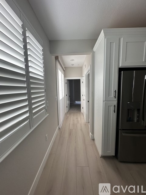 A long hallway with white shutters on the windows.
