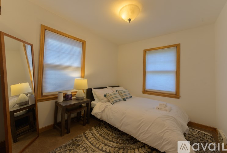 A bedroom with a bed, two lamps, and a window.