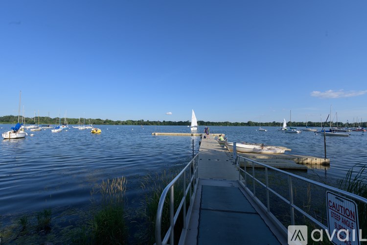 A white sailboat is docked at a pier with a caution sign.