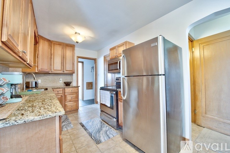 A kitchen with a granite counter top and wooden cabinets.