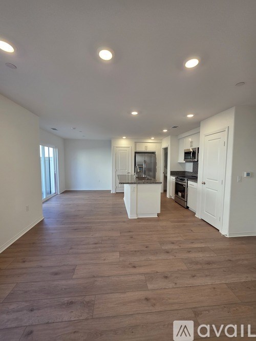 A spacious kitchen with white cabinets and a wooden floor.