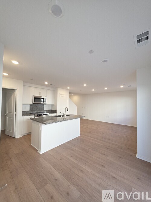 A kitchen with a white island and wooden floors.