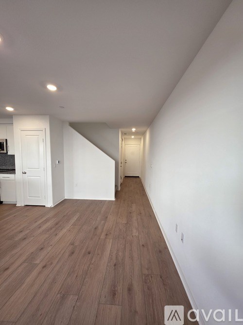 A long hallway with wood floors and white walls.