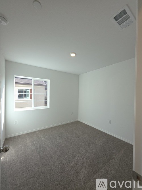 A room with a window and a carpeted floor.