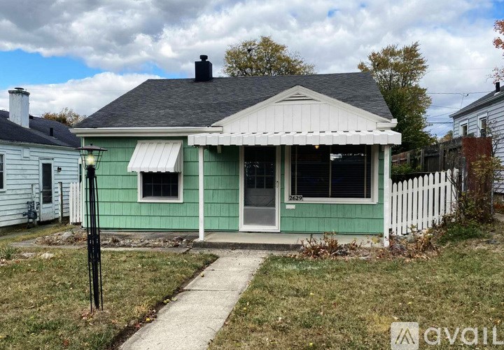 A green house with a white picket fence in front.