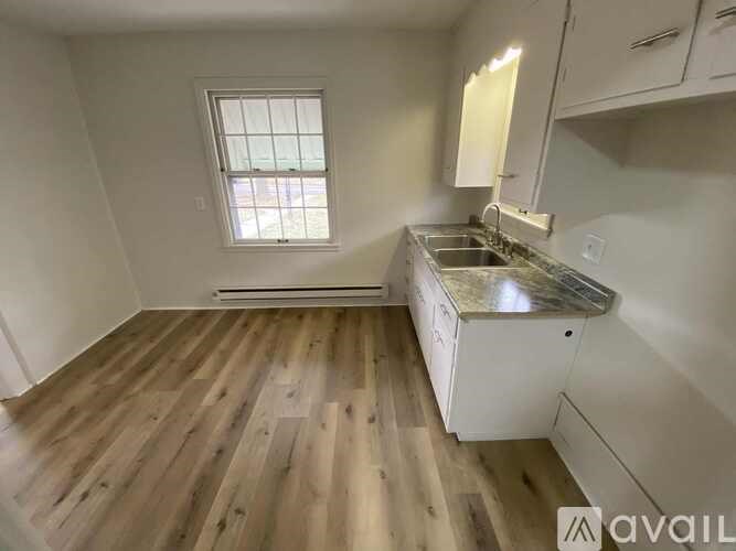 A kitchen with wooden floors and white cabinets.
