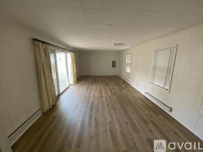 A spacious room with wooden flooring and white walls.