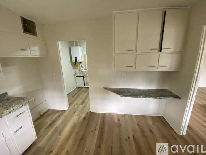 A kitchen with white cabinets and a wooden floor.
