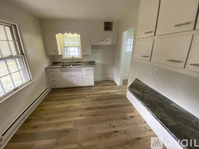 A kitchen with wooden floors and white cabinets.