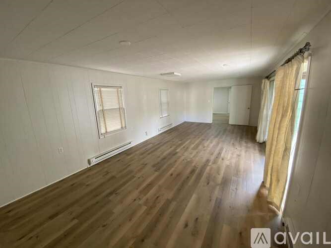 A room with wooden flooring and a window with blinds.