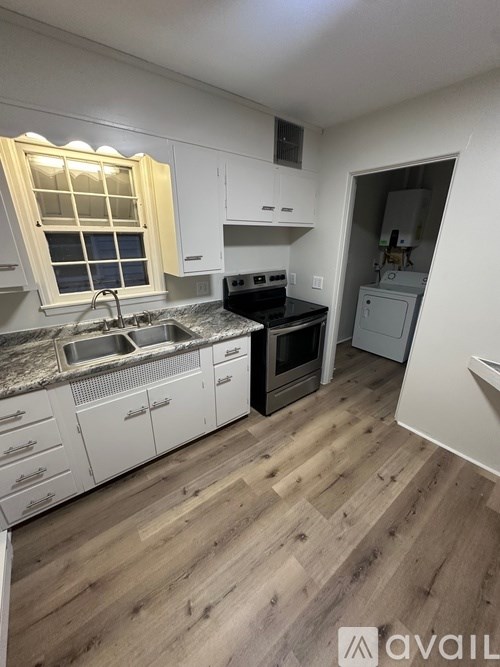 A kitchen with wooden floors and white cabinets.