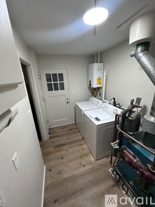 A room with a white fridge and a white door with a window.
