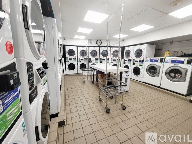 A laundromat with a shopping cart in the middle of the room.