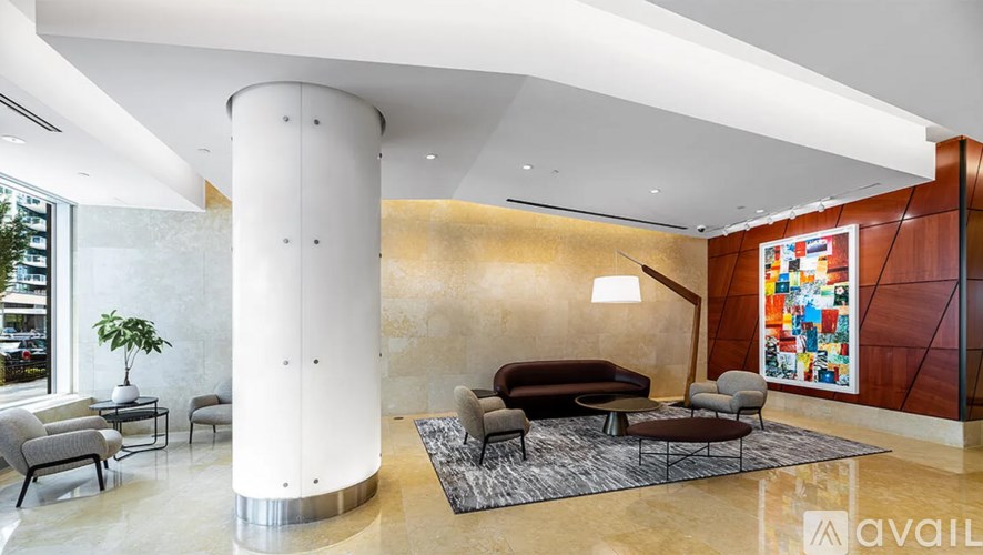 A modern living room with a white column and a large abstract painting on the wall.