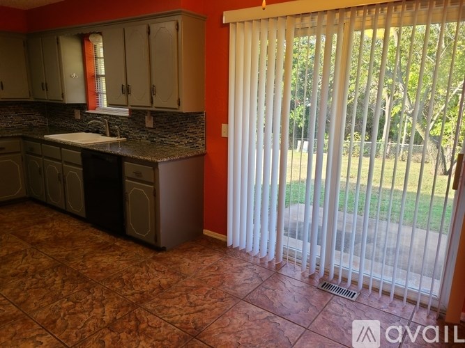 A kitchen with brown tiled floors and white blinds on the window.