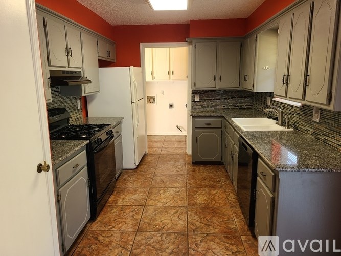 A kitchen with a tile floor and a mix of white and dark appliances.