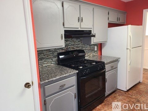 A kitchen with a black stove top oven and a white refrigerator.