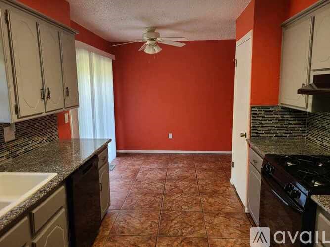 A kitchen with orange walls and a tiled floor.