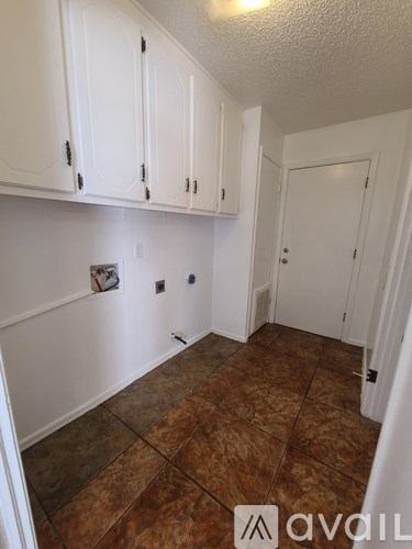 A room with white cabinets and brown tile flooring.