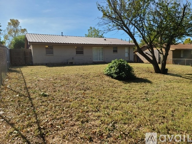 A house with a brown roof and a tree in front of it.