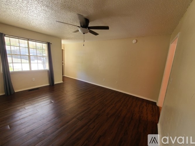 A room with a ceiling fan and wooden flooring.