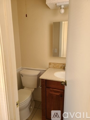 A bathroom with a toilet, sink and mirror.