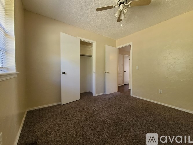 A room with a carpeted floor and a ceiling fan.