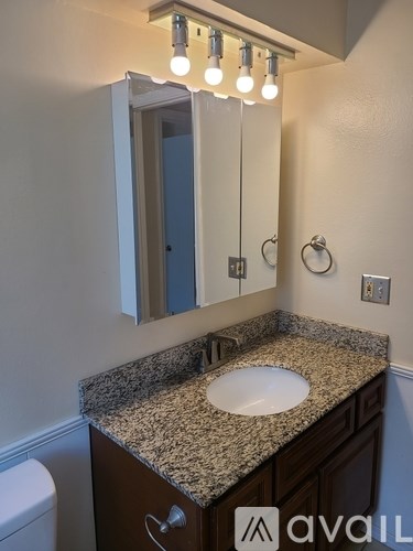 A bathroom with granite countertop and a wall-mounted light fixture.