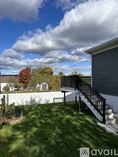 A backyard with a white fence and a deck.
