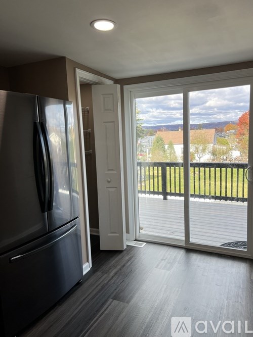 A kitchen with a refrigerator and a sliding glass door leading to a balcony.